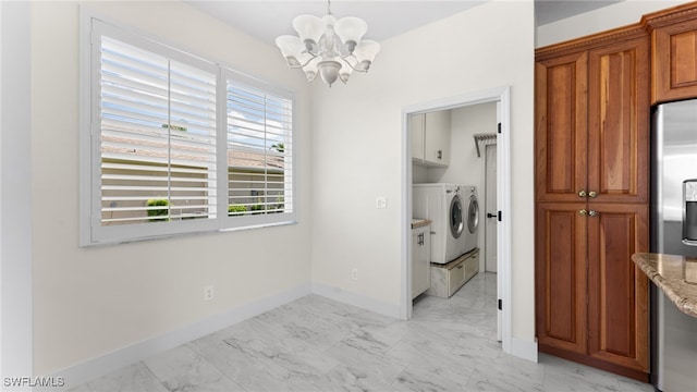 laundry area featuring cabinets, washer and clothes dryer, and an inviting chandelier