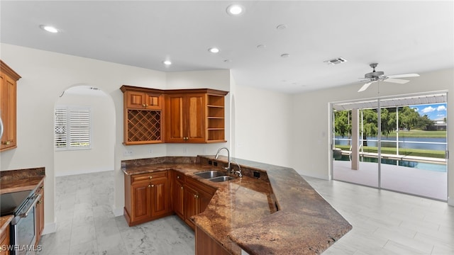 kitchen featuring dark stone counters, sink, kitchen peninsula, ceiling fan, and electric range