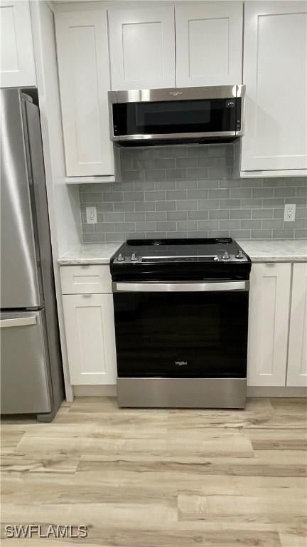 kitchen featuring light wood-type flooring, white cabinets, and appliances with stainless steel finishes