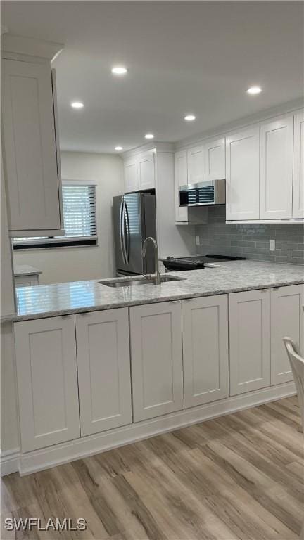 kitchen with white cabinetry, light hardwood / wood-style floors, range hood, and refrigerator