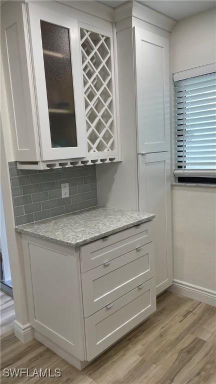 bar featuring white cabinetry and light hardwood / wood-style flooring