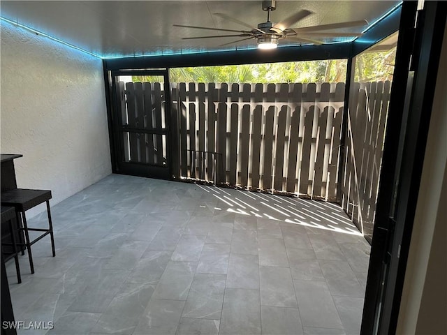 unfurnished sunroom with ceiling fan