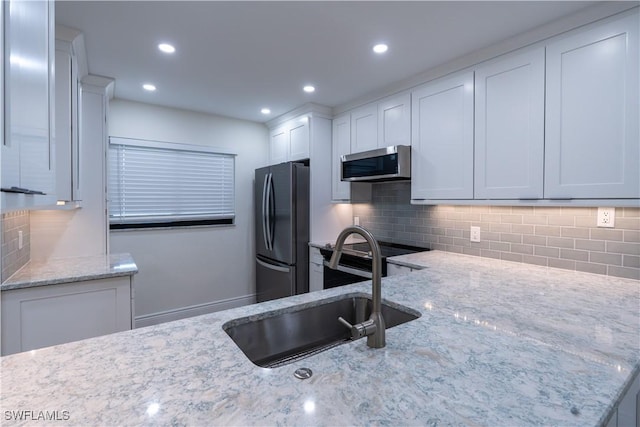 kitchen featuring sink, white cabinets, decorative backsplash, light stone counters, and stainless steel appliances