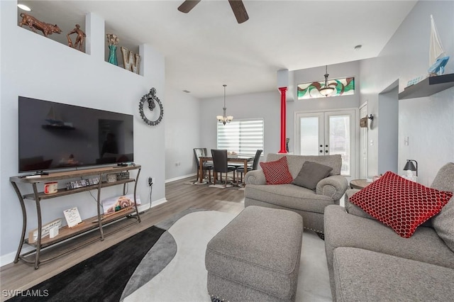 living room featuring ceiling fan with notable chandelier, wood-type flooring, and french doors