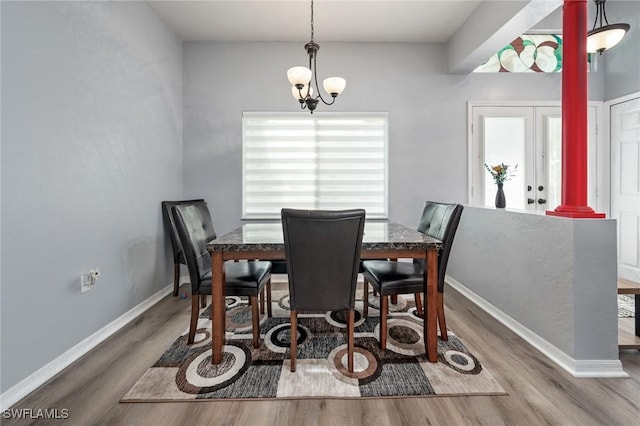 dining area with decorative columns, hardwood / wood-style floors, and a chandelier