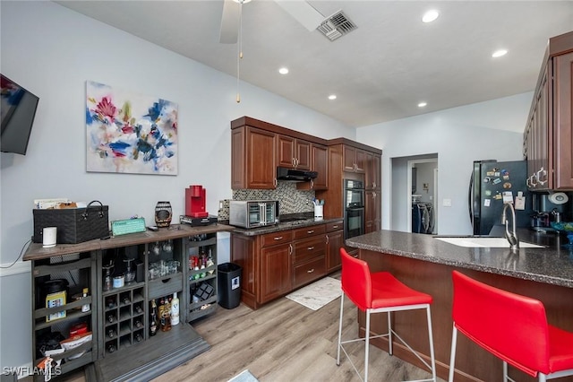 kitchen with ceiling fan, decorative backsplash, light wood-type flooring, black appliances, and sink