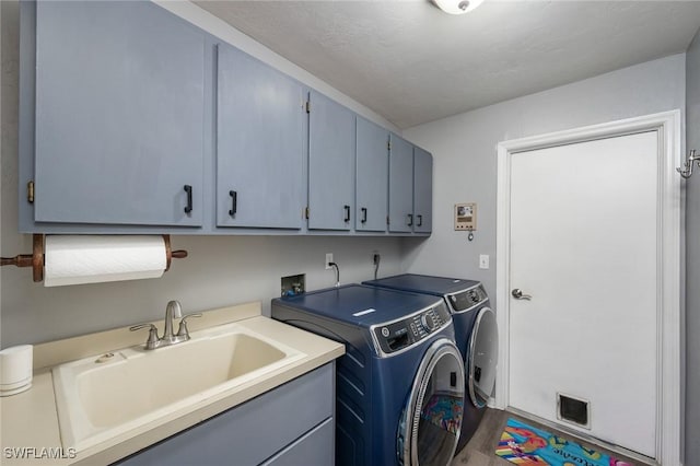 laundry room with hardwood / wood-style floors, sink, washer and dryer, and cabinets