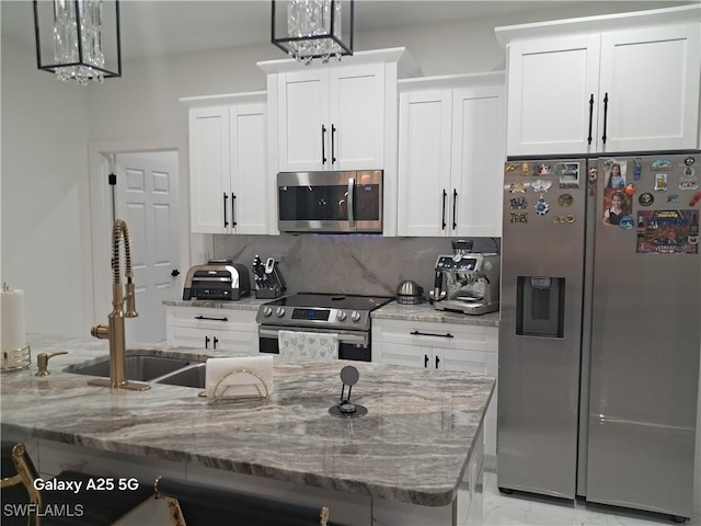 kitchen with stainless steel appliances, pendant lighting, white cabinets, and tasteful backsplash