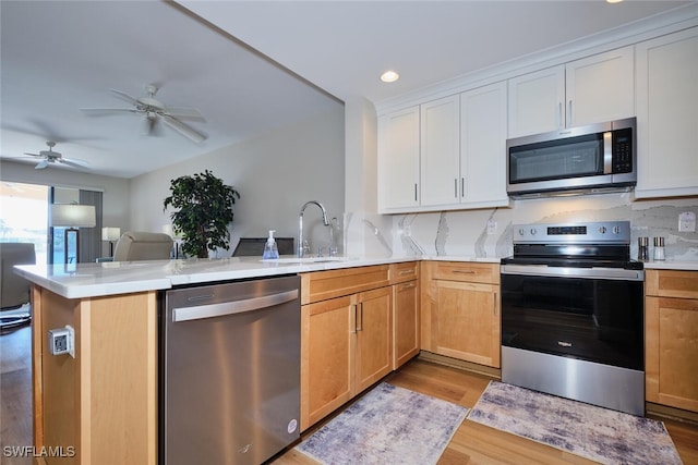 kitchen featuring white cabinetry, stainless steel appliances, sink, kitchen peninsula, and light wood-type flooring