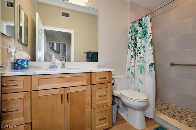 bathroom featuring toilet, walk in shower, and vanity