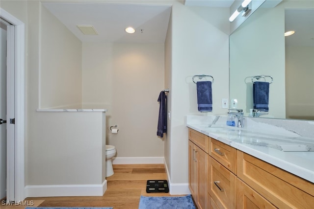 bathroom with hardwood / wood-style floors, toilet, and vanity