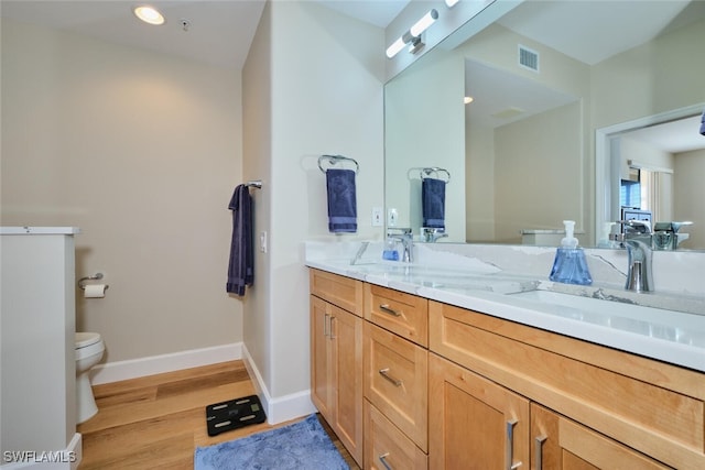 bathroom with toilet, vanity, and hardwood / wood-style flooring