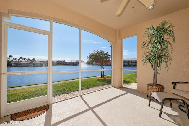 sunroom featuring ceiling fan, a healthy amount of sunlight, and a water view