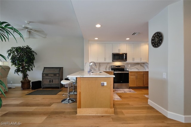 kitchen featuring a kitchen bar, appliances with stainless steel finishes, tasteful backsplash, white cabinets, and a center island