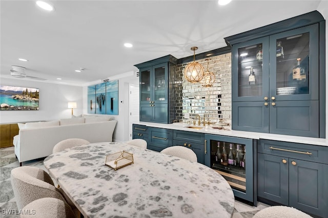 bar featuring blue cabinetry, decorative light fixtures, beverage cooler, ornamental molding, and sink