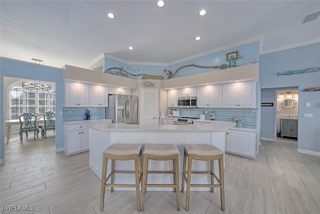 kitchen featuring stainless steel appliances, a kitchen breakfast bar, white cabinets, and a kitchen island