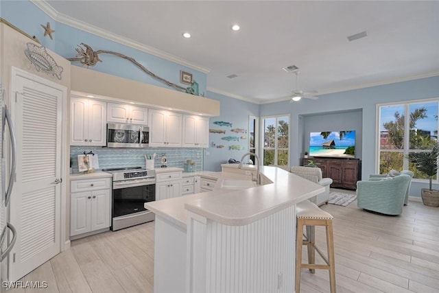 kitchen with sink, a kitchen bar, white cabinets, and appliances with stainless steel finishes