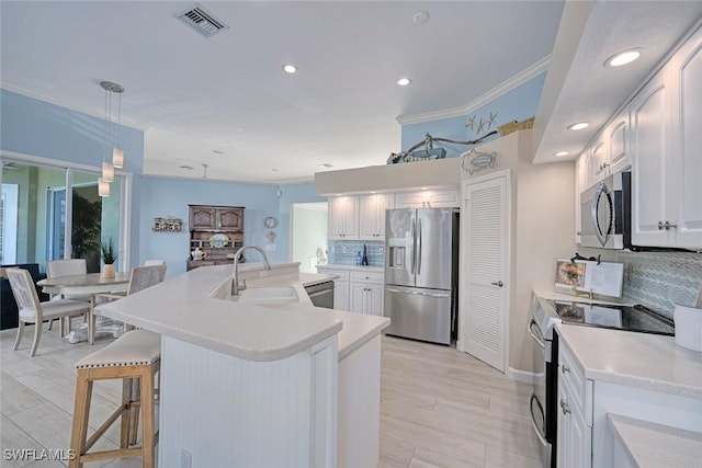 kitchen featuring appliances with stainless steel finishes, white cabinetry, sink, decorative backsplash, and hanging light fixtures