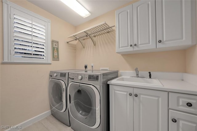 clothes washing area featuring cabinets, sink, washing machine and dryer, and light tile patterned floors