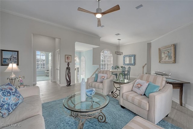 living room with a wealth of natural light, ornamental molding, ceiling fan, and light wood-type flooring