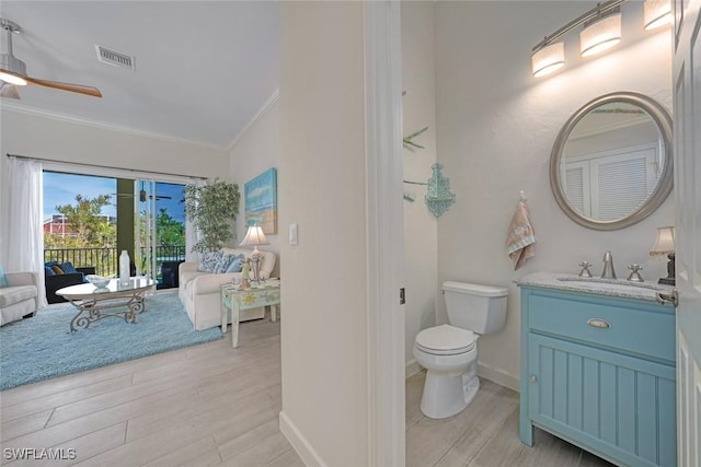 bathroom featuring hardwood / wood-style flooring, ornamental molding, vanity, ceiling fan, and toilet