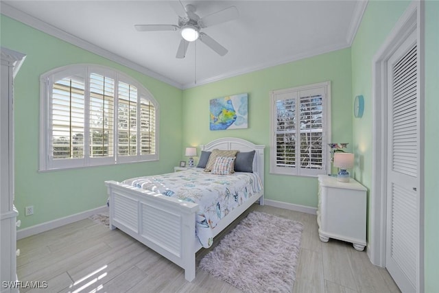 bedroom featuring crown molding, light wood-type flooring, ceiling fan, and a closet