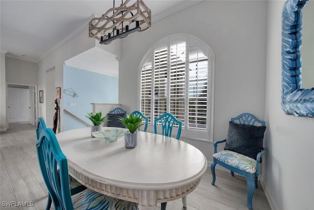 dining area with ornamental molding and light hardwood / wood-style floors