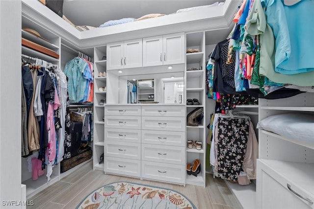 walk in closet with light hardwood / wood-style flooring