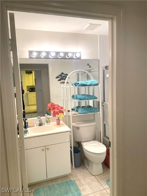 bathroom with visible vents, toilet, a shower with shower door, tile patterned flooring, and vanity