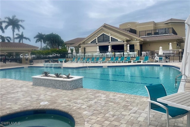 community pool with fence, a community hot tub, and a patio