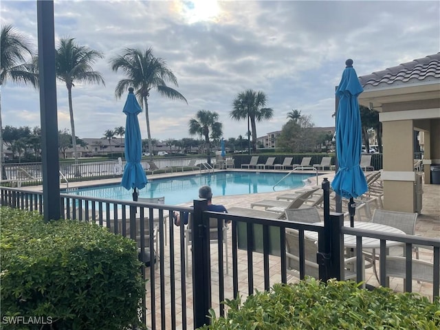 community pool with a patio area and fence