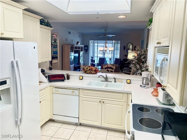 kitchen with light tile patterned floors, light countertops, a sink, white appliances, and a peninsula