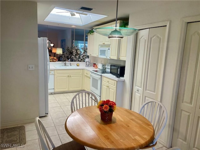 kitchen with light tile patterned floors, light countertops, visible vents, a sink, and white appliances