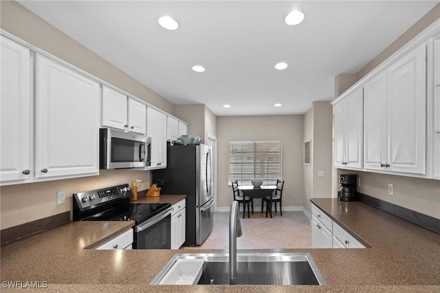 kitchen featuring appliances with stainless steel finishes, white cabinetry, sink, kitchen peninsula, and light tile patterned floors