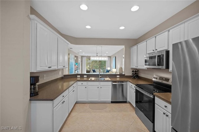 kitchen featuring light tile patterned floors, appliances with stainless steel finishes, white cabinetry, and sink