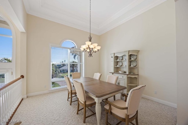 dining space with crown molding, light carpet, an inviting chandelier, and a tray ceiling