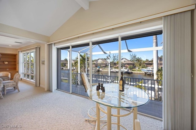 entryway featuring carpet floors, a water view, and vaulted ceiling with beams