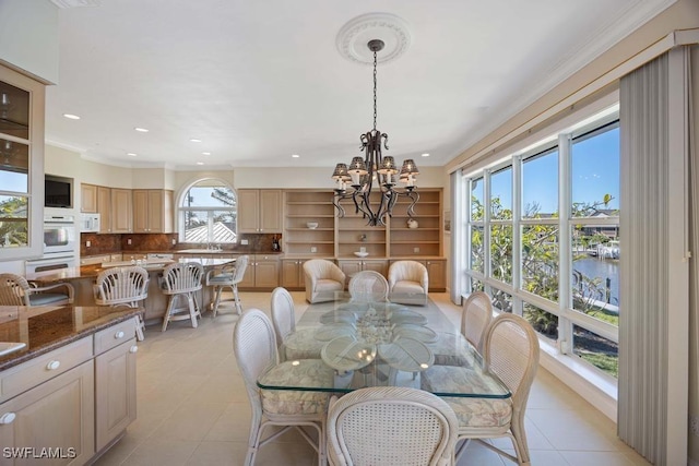 dining room featuring a notable chandelier, light tile patterned floors, plenty of natural light, and a water view