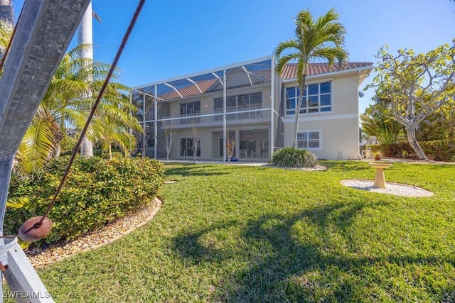 back of property with glass enclosure and a lawn