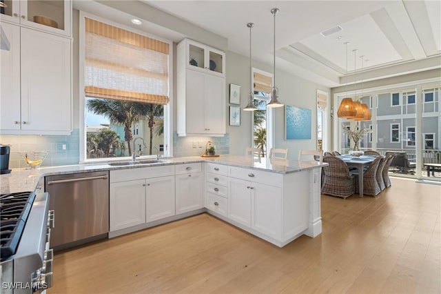 kitchen featuring appliances with stainless steel finishes, pendant lighting, sink, white cabinets, and light wood-type flooring