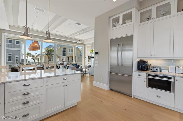 kitchen with pendant lighting, tasteful backsplash, white cabinetry, light hardwood / wood-style floors, and stainless steel appliances