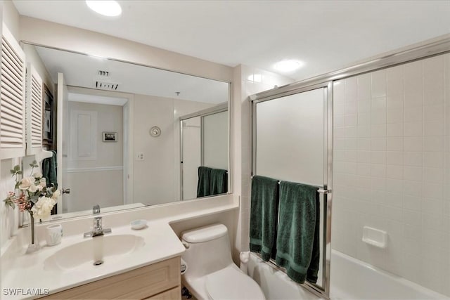 full bathroom with enclosed tub / shower combo, vanity, and toilet