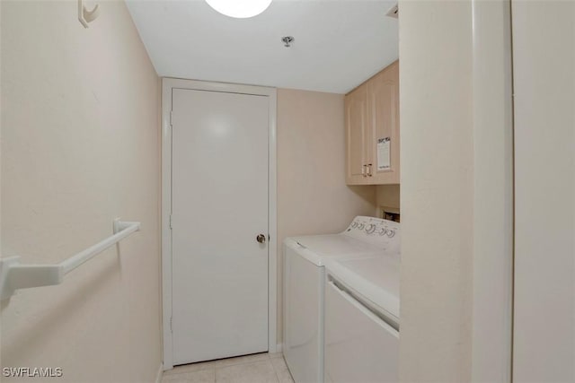 laundry area featuring light tile patterned floors, washer and clothes dryer, and cabinets