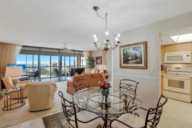 tiled dining room with a water view, a wall of windows, and ceiling fan with notable chandelier