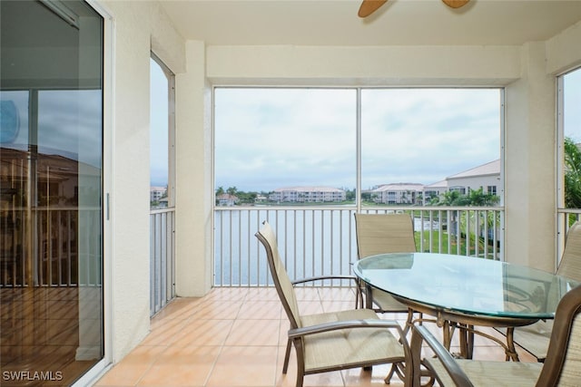 sunroom with ceiling fan, a healthy amount of sunlight, and a water view