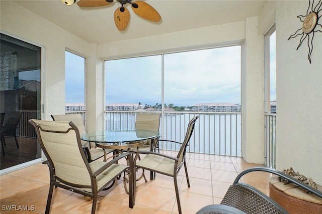 sunroom / solarium with ceiling fan, a wealth of natural light, and a water view