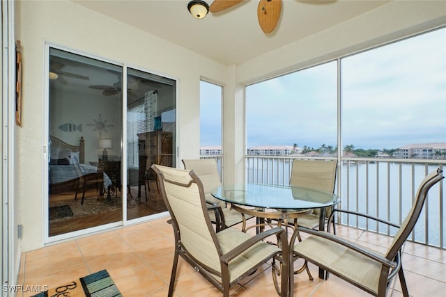 sunroom / solarium featuring a water view and ceiling fan