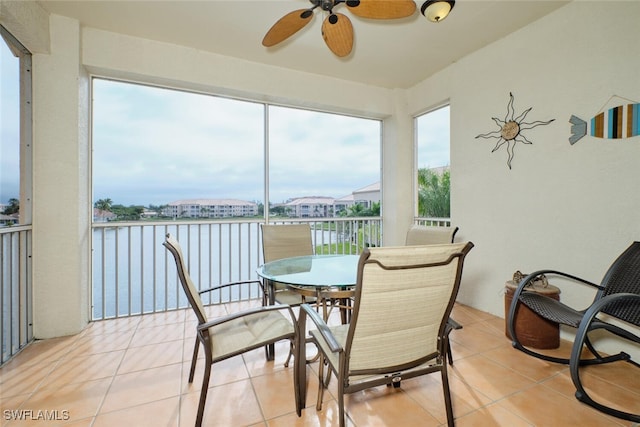 sunroom / solarium featuring ceiling fan, a wealth of natural light, and a water view