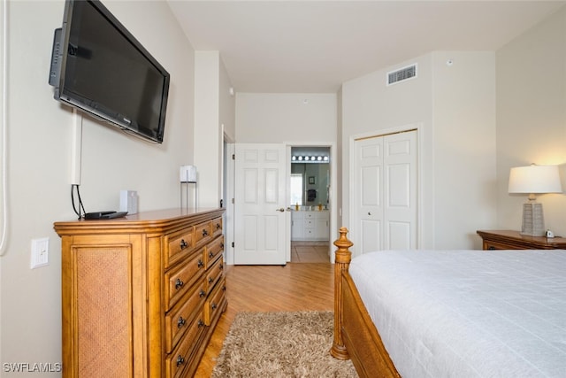 bedroom with light hardwood / wood-style floors, ensuite bathroom, and a closet