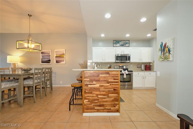 kitchen with light tile patterned floors, stainless steel appliances, pendant lighting, and decorative backsplash